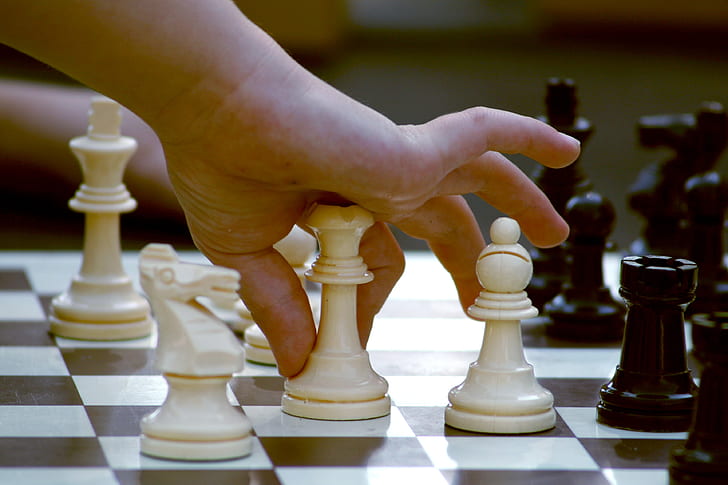 Child's hand moving a chess piece on a chess board